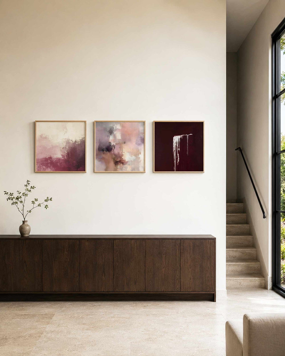 Interieurpresentatie van een driedelige vierkante posterset met abstracte roze bordeaux