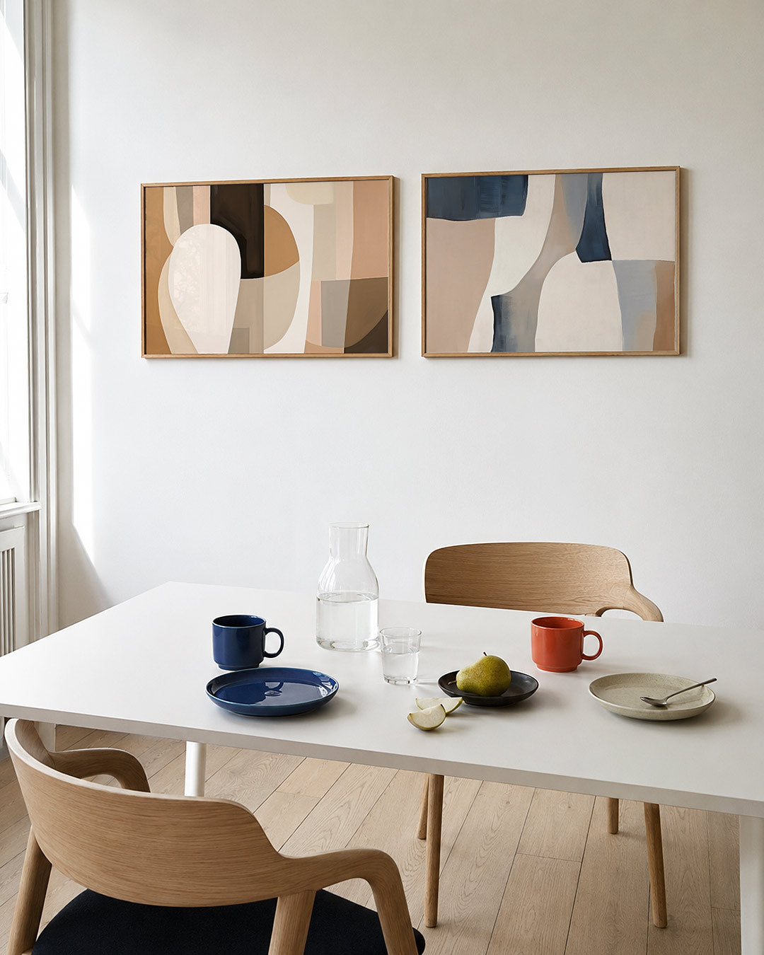 Twee liggende posters met zachte, aardse tinten en vloeiende vormen, aan de muur in een interieur
