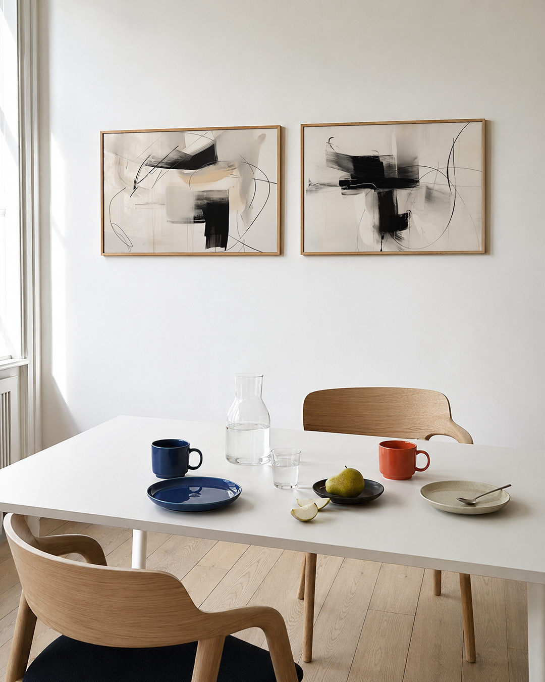 Twee liggende posters met vloeiende zwarte en beige vlakken, aan de muur in een interieur