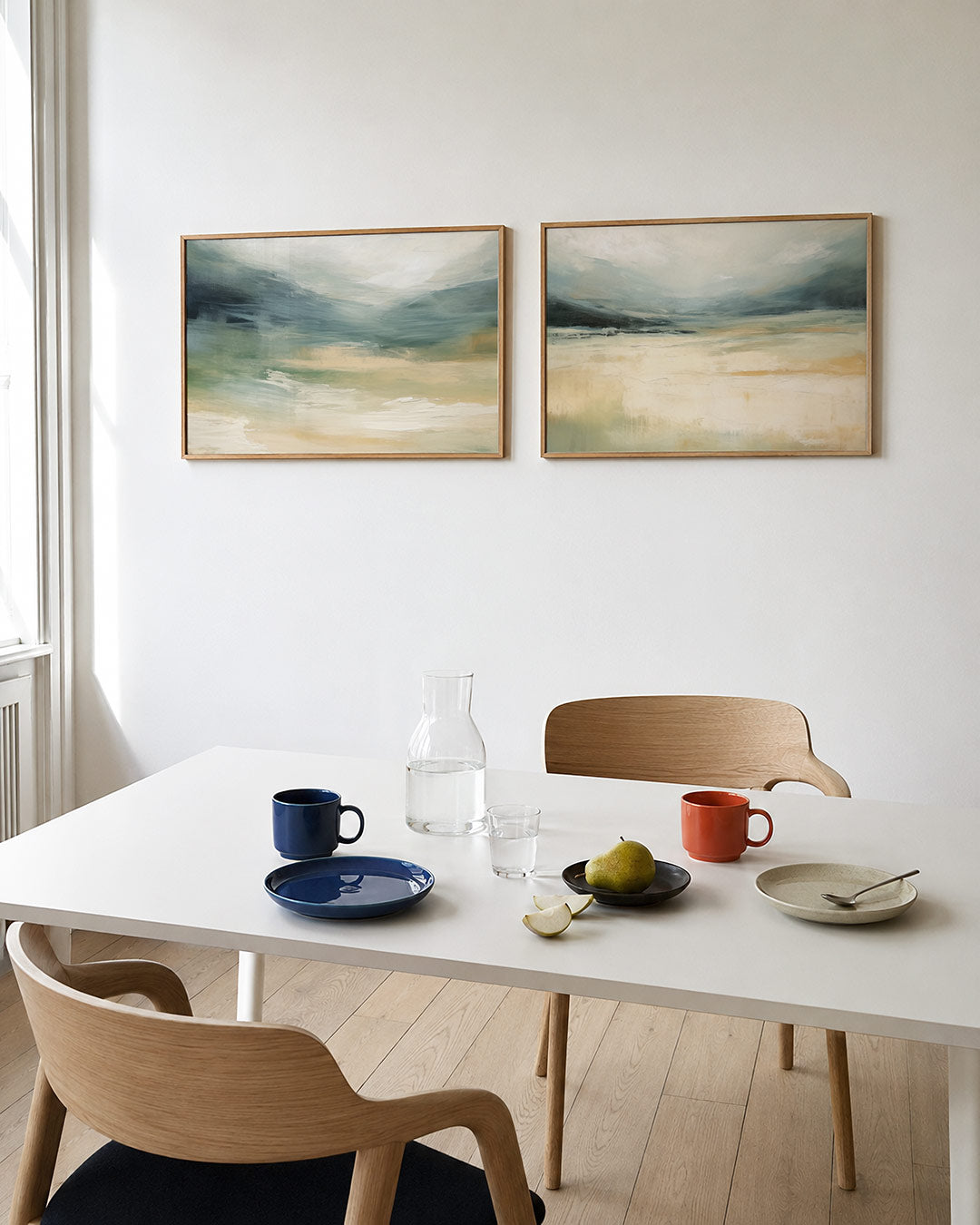 Twee liggende posters met zachte overgangen van blauw en beige, met vloeiende penseelstreken, aan de muur in een interieur