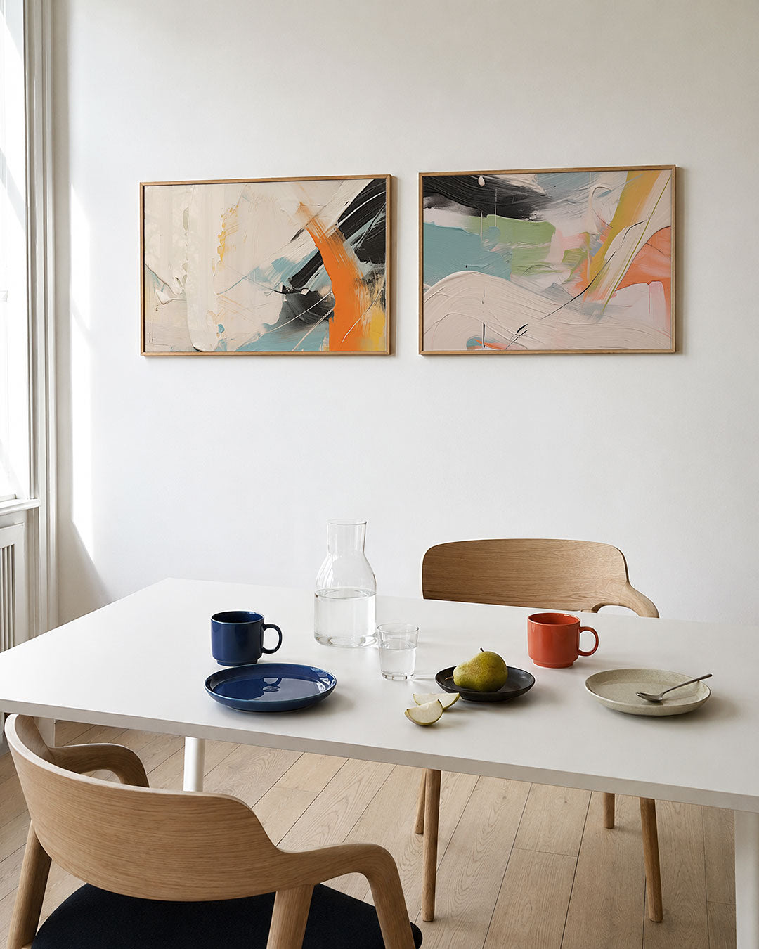 Tweedelige posterset met vloeiende witte, oranje en blauwe kleurvlakken, met krachtige zwarte, getoond in een interieur